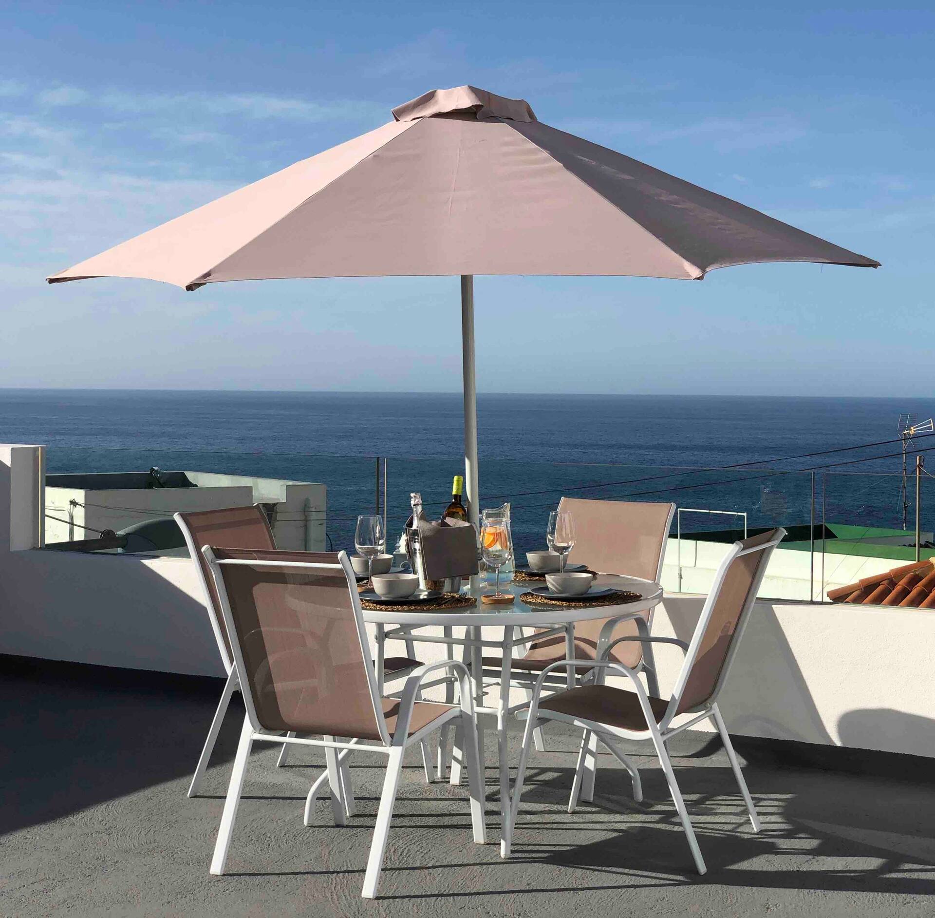 Mesa puesta bajo una sombrilla en la azotea, con el Atlántico al fondo